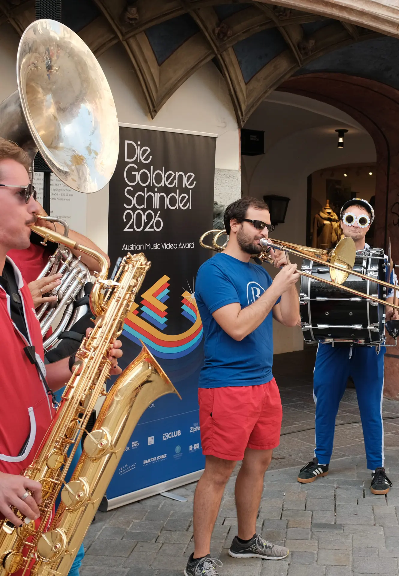 A brass band playing in front of the 2026 poster