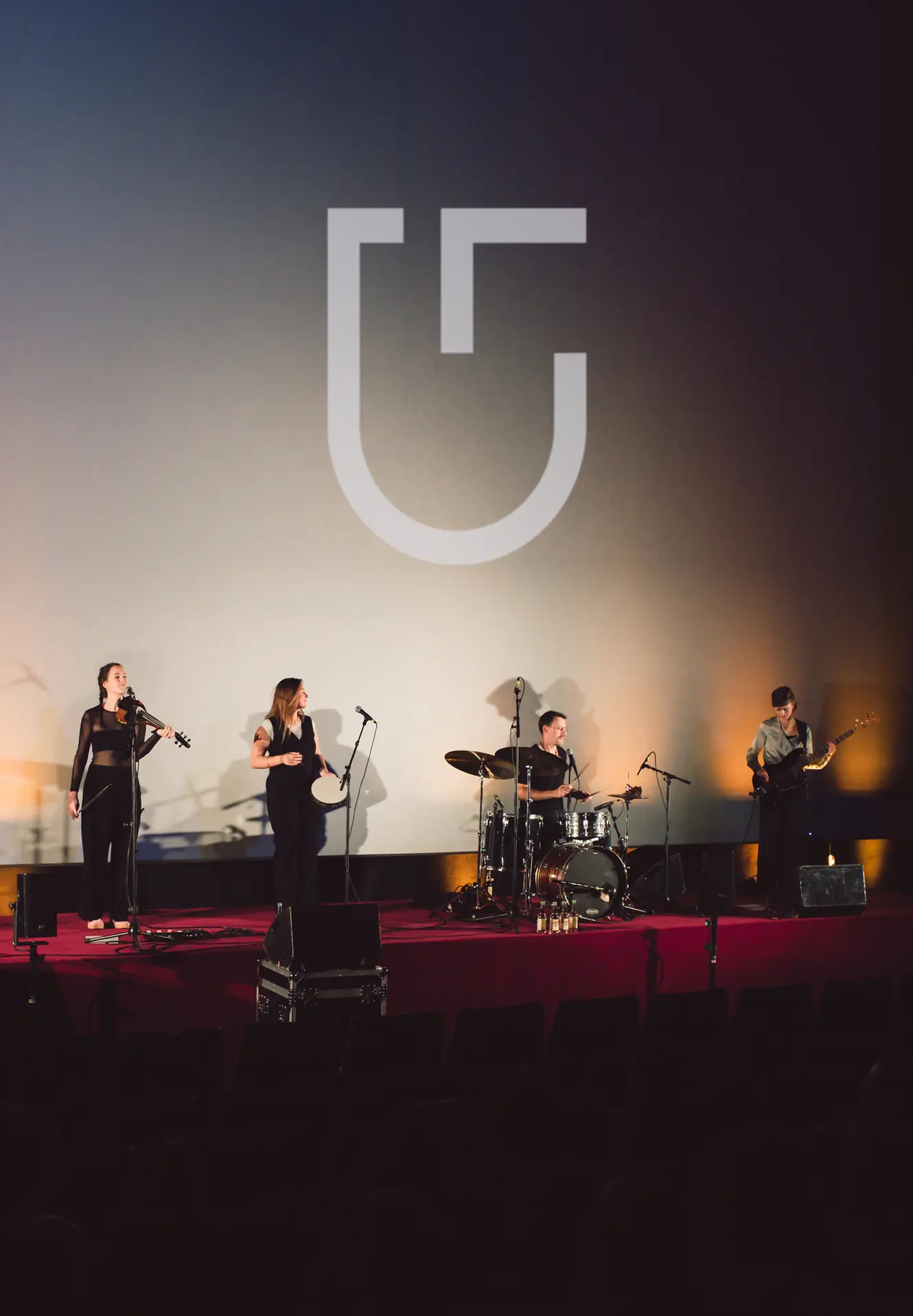 A band on stage beneath the shingle on the cinema screen