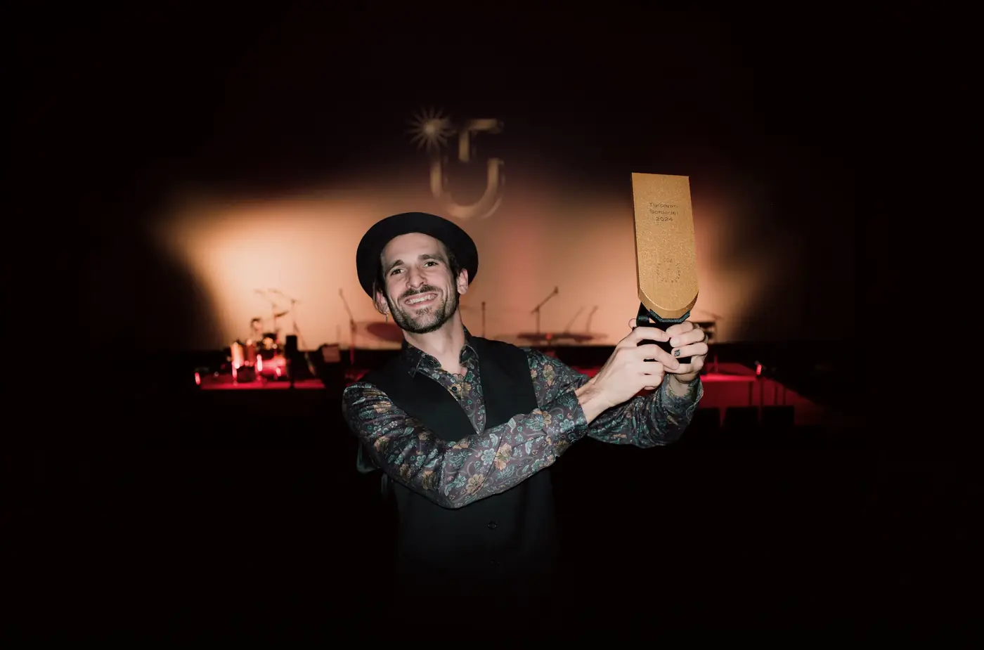 A winner on stage holding up the golden shingle trophy